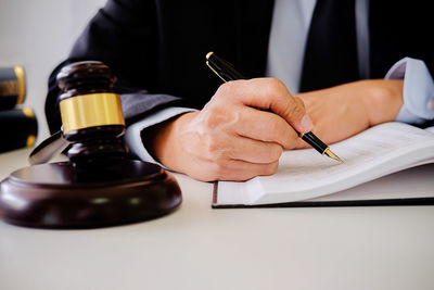 Cropped hand of lawyer writing in book at courtroom