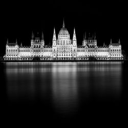 Illuminated cathedral by river at night