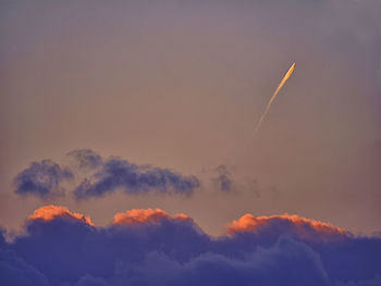 Low angle view of vapor trails in sky during sunset