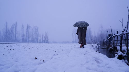 Rear view of woman walking on snow covered landscape