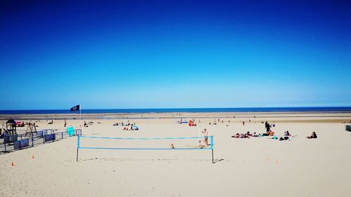 Group of people on beach against clear blue sky