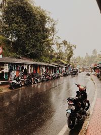 People riding bicycle on road against sky in city