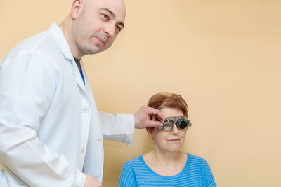 A male optometrist checks the eyesight of an adult woman with a trial frame