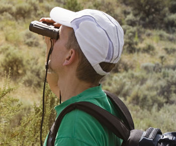 Close-up of man looking through binoculars at forest