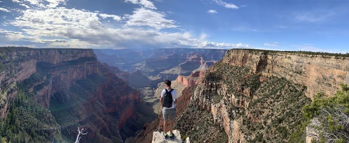 Panoramic shot of person standing on rock against sky