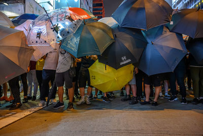 Rear view of people standing on street in rain