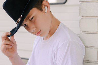 Portrait of young man holding camera against wall