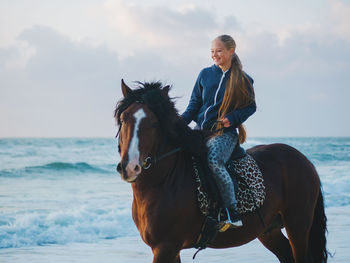 Young woman horseback riding at beach