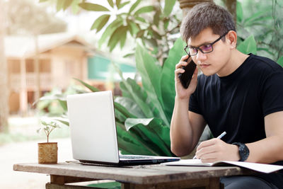 Man using mobile phone while sitting on table