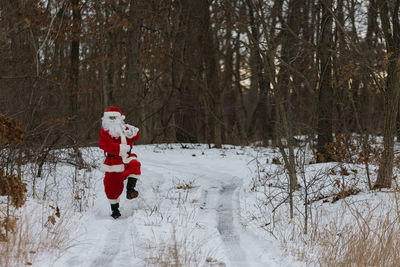 Santa walking on snow covered field during winter