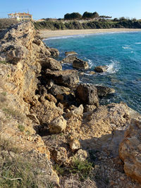 Rock formation on sea shore against sky