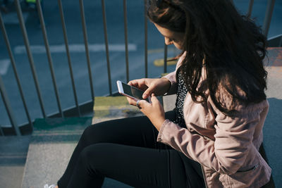 High angle view of woman using smart phone while sitting on staircase