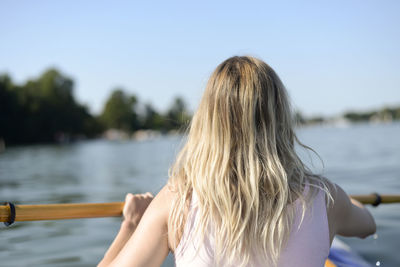 Rear view of woman rowing boat against sky