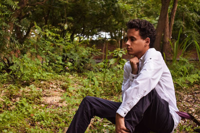 Side view of young man sitting in forest