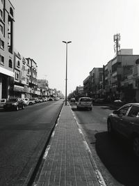 Cars on street in city against clear sky