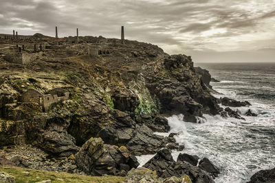 Rocks on shore by sea against sky