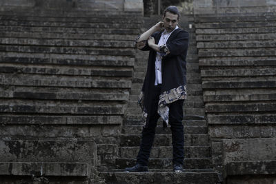 Young man looking away while standing on steps 