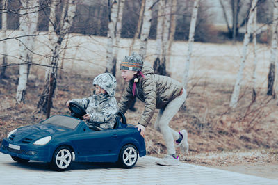 Two happy children playing with big old toy car in countryside, outdoors.