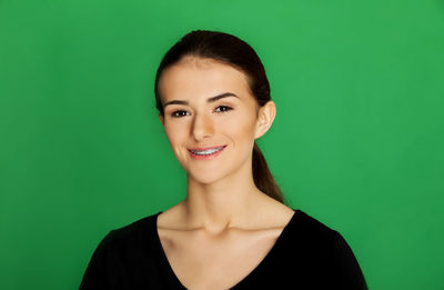 Portrait of a smiling young woman over green background
