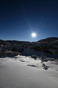 Scenic view of snowcapped mountains against bright sun