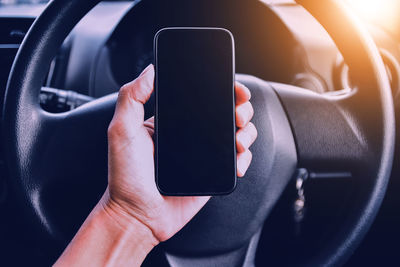 Close-up of person holding mobile phone in car