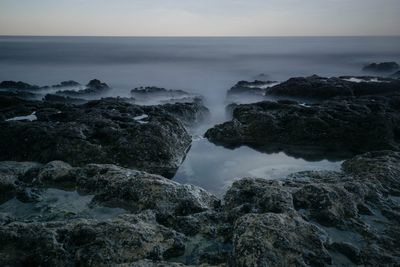 Scenic view of rocks in sea against sky during sunset