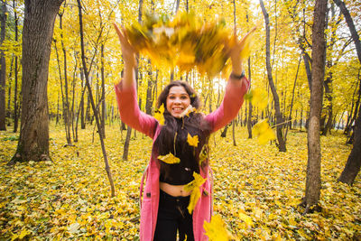 Portrait of a smiling young woman with yellow autumn leaves