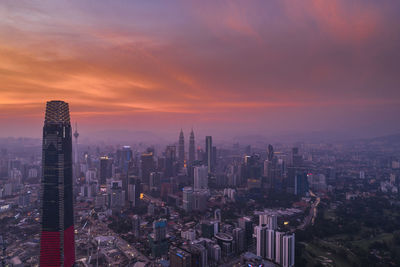 Aerial view of buildings in city against sky during sunset