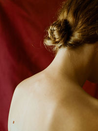 Rear view of a young beautiful woman.  she does't face the camera. red curtain background. 