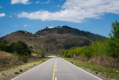 Road by mountains against sky