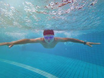 Man with arms outstretched swimming in pool