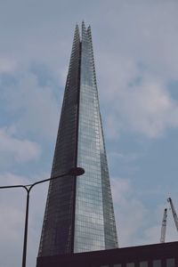 Low angle view of modern building against cloudy sky