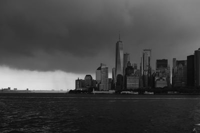 Sea by modern buildings against sky in city