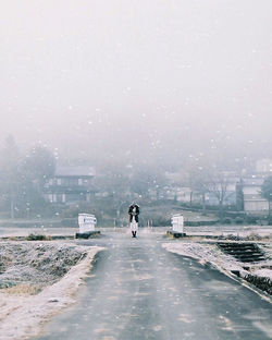 People on wet road in city during winter