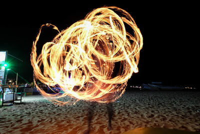 Close-up of illuminated light on beach against sky at night