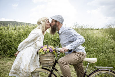 Rear view of couple kissing on field