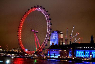 Illuminated ferris wheel in city at night