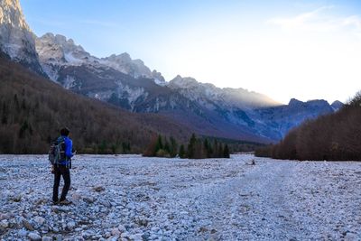 Rear view of hiker standing on ground at mountains