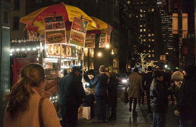 People at illuminated street market in city