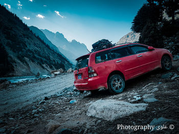 Red car on mountain road against sky