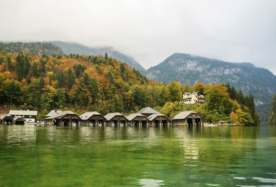 Houses by lake and buildings against sky