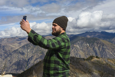 Male in flannel taking selfie with cell phone