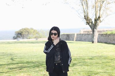 Young woman wearing sunglasses standing on field