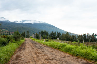 Road amidst field against sky