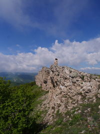 Distant woman sitting on the top of the mountain