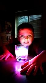 Portrait of smiling boy holding glass on table