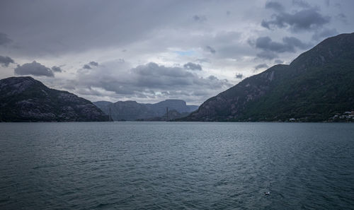 Scenic view of sea by mountains against sky