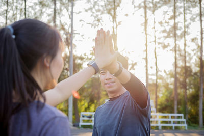 Friends high-fiving while exercising at public park