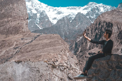 Man taking selfie while sitting on mountain