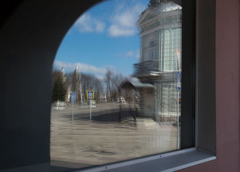 Trees by building against sky seen through window